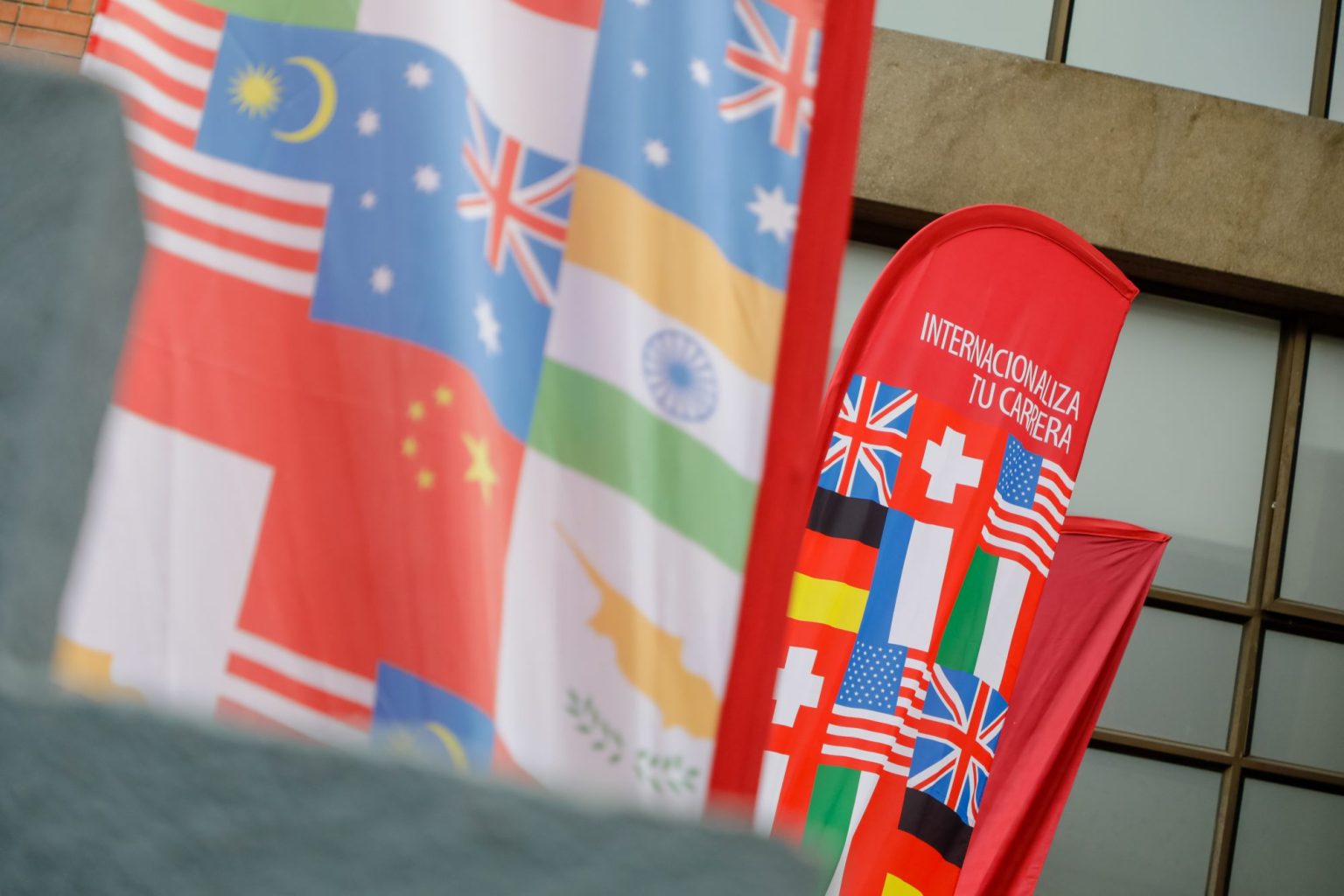 Red vertical banners featuring multiple national flags and the slogan 'Internacionaliza tu carrera' visible on the front banner.